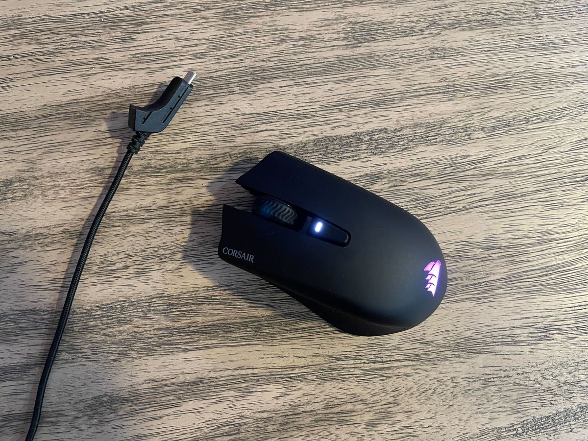 A Corsair Harpoon mouse sits on a wooden table