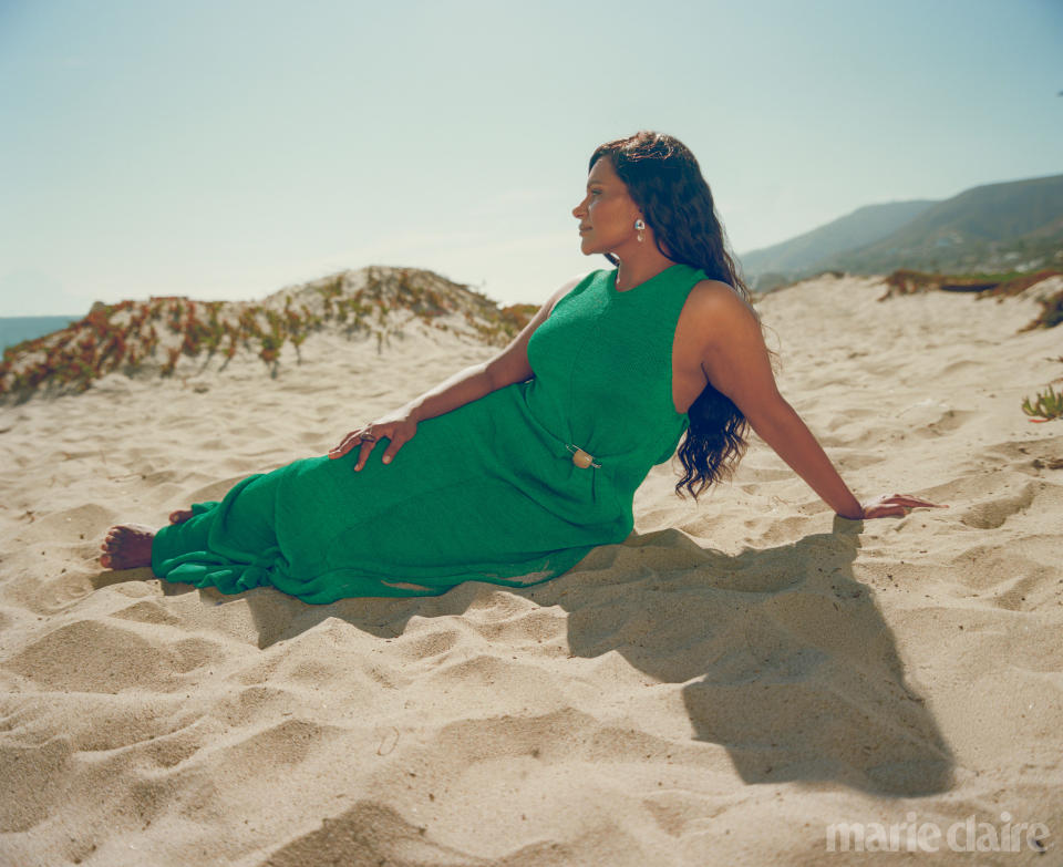 Mindy Kaling in a green dress lounging in the sand.  (Photo: Kanya Iwana for Marie Claire)