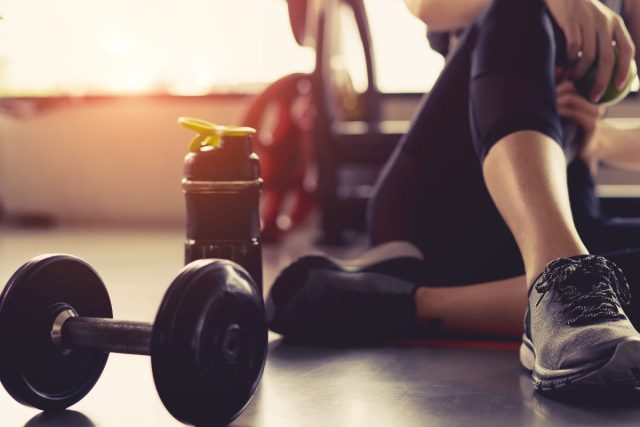 Woman sitting with dumbbells in the gym