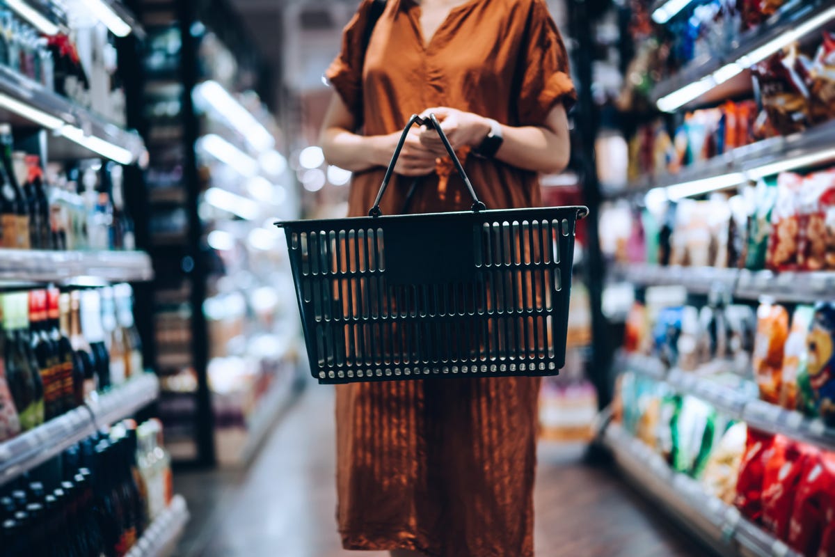 Person in a long brown dress is browsing a grocery store aisle.