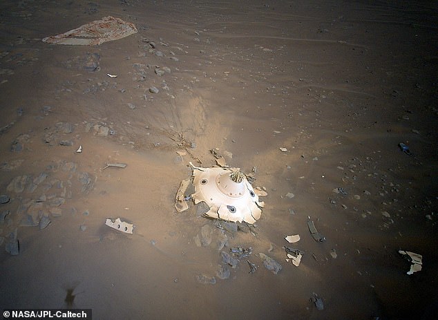 The Ingenuity helicopter captured an image with Perseverance of the landing gear used upon its arrival.  Images is a parachute and the cone-shaped outer shell that protected the rover in space