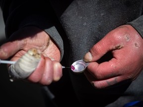 A man draws an unknown illicit substance into a syringe before injecting it into his arm as people gather for a rally and march to demand the government ensure a secure supply of illicit substances, Wednesday, April 14, 2021 in Vancouver to ensure drugs.  Researchers at The University of British Columbia have found that limited access to HIV care and prevention services during the early COVID-19 lockdowns was linked to a 