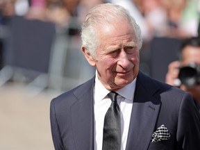 King Charles III  looks at floral tributes to the late Queen Elizabeth II outside Buckingham Palace on September 9, 2022 in London.