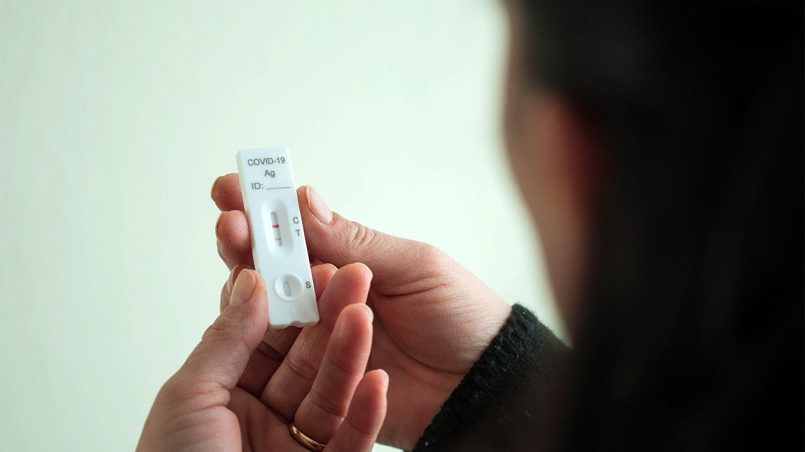 A photo of a woman holding a positive COVID test.