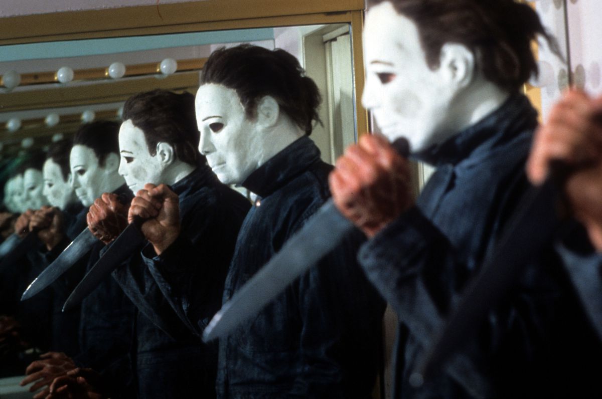 An endless line of Michael Myers in his emotionless white mask and holding a knife in a mirror in Halloween 4: The Return of Michael Myers.