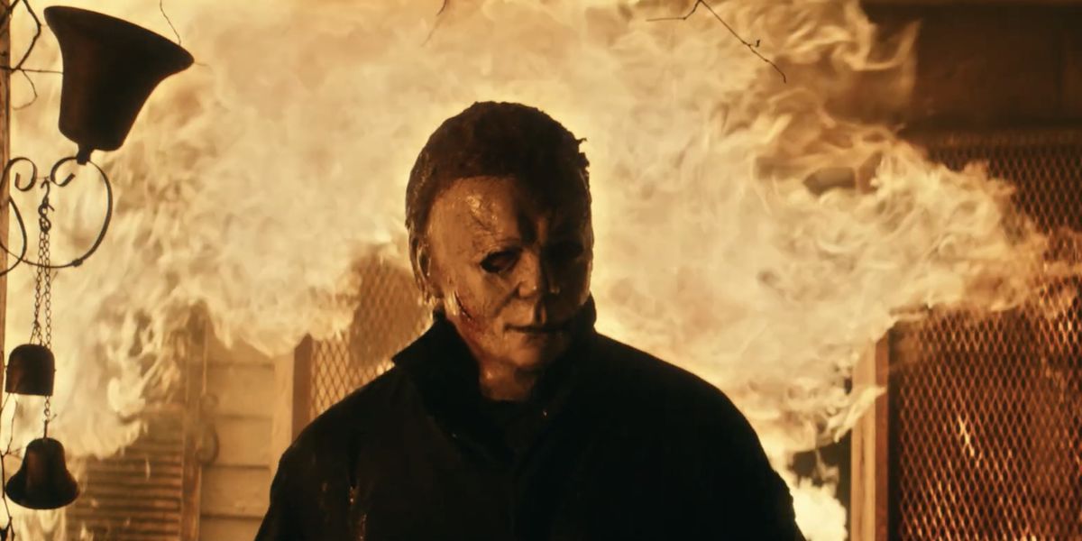 Michael Myers emerges from a burning house in Halloween Kills.  The background is mostly flame.