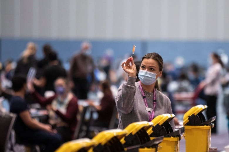 A medical worker wearing a mask holds up a dose of the COVID-19 vaccine at a vaccination clinic in Vancouver in January 2022. 