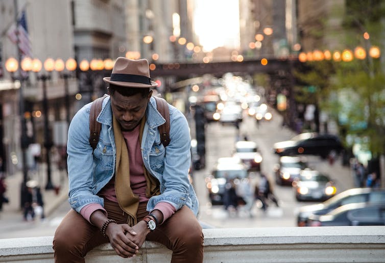 Man sitting on a ledge above a busy street