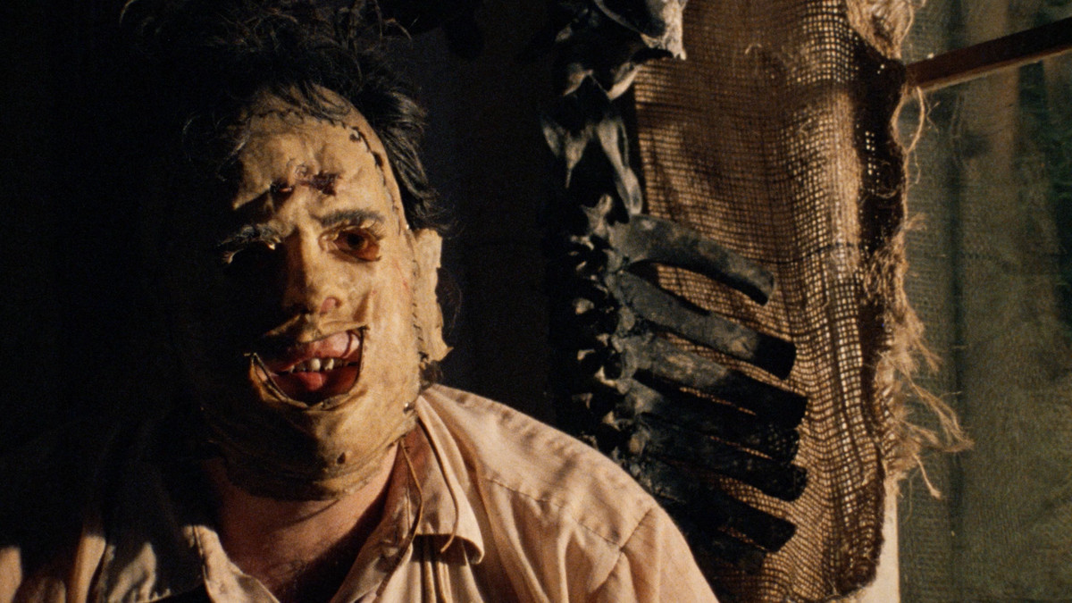 Leatherface is pensive in The Texas Chainsaw Massacre with a mask on his face