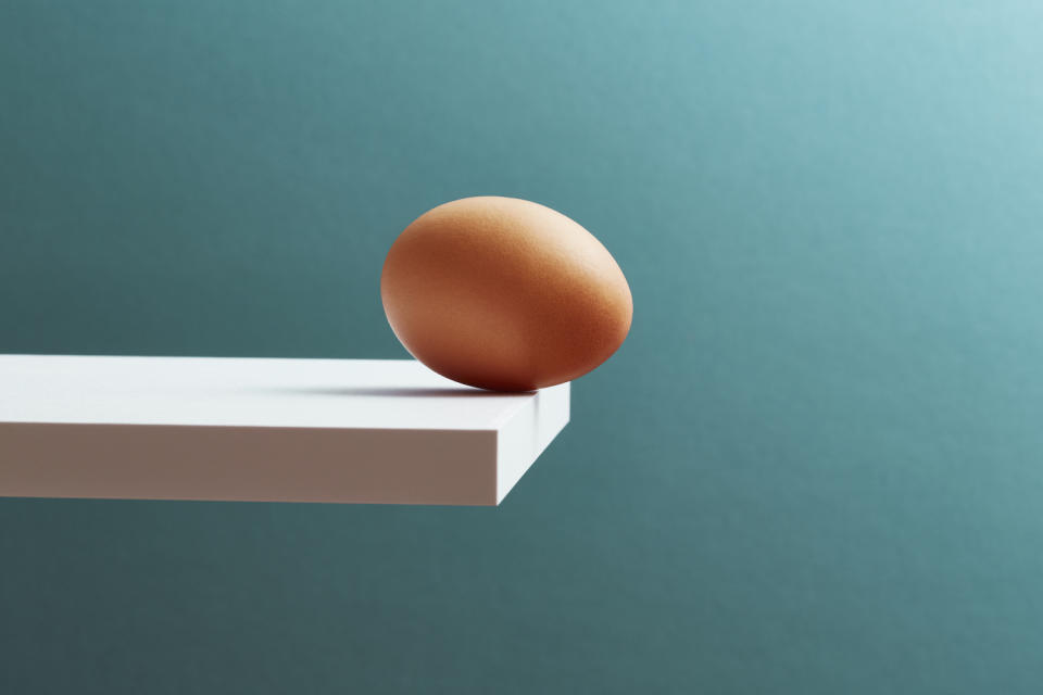 An egg wiggling on the edge of a board