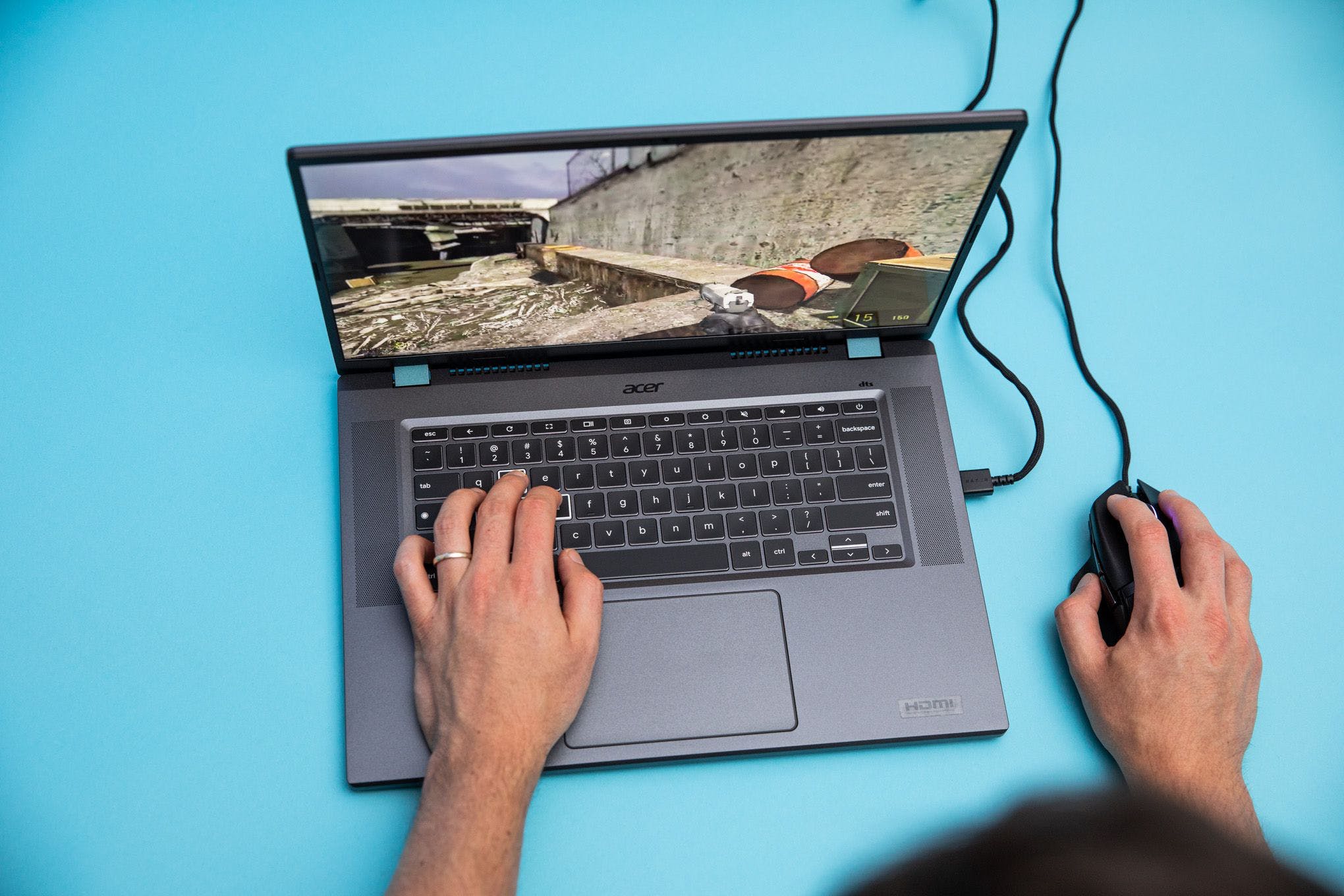 The Acer Chromebook 516 GE with a mouse attached playing Half Life 2.  The author's left hand rests on the laptop's W, A, S, and D keys to move.