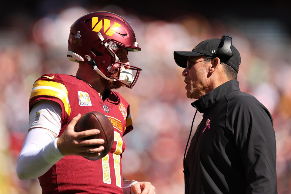 LANDOVER, MARYLAND - OCTOBER 9: Carson Wentz #11 of the Washington Commanders talks to head coach Ron Rivera during the first half against the Tennessee Titans at FedExField on October 9, 2022 in Landover, Maryland.  (Photo by Scott Taetsch/Getty Images)