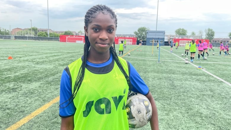 A girl wearing a jersey holds a soccer ball. 