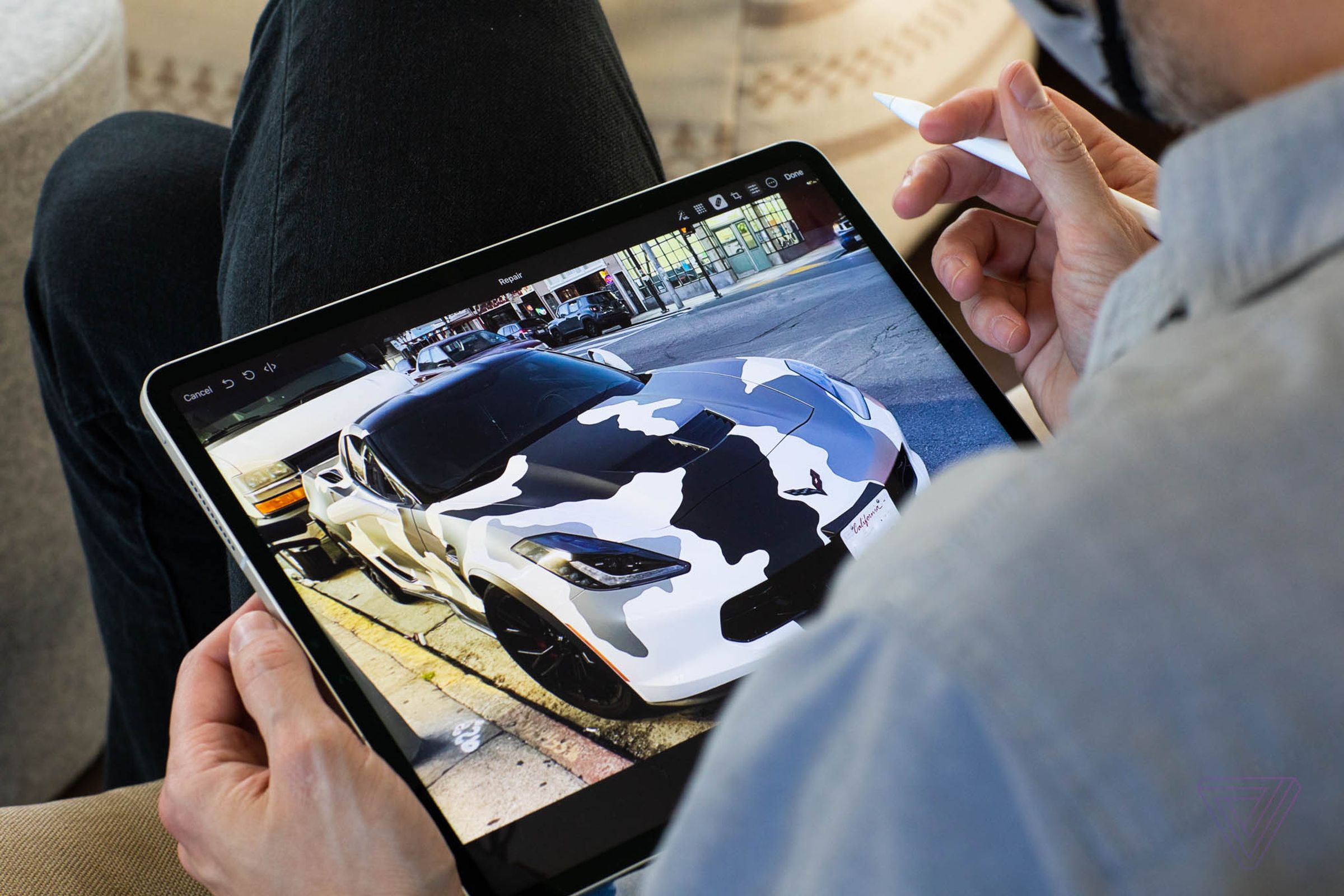 The iPad Pro on a person's lap as they edit a photo on the tablet with an Apple Pencil.